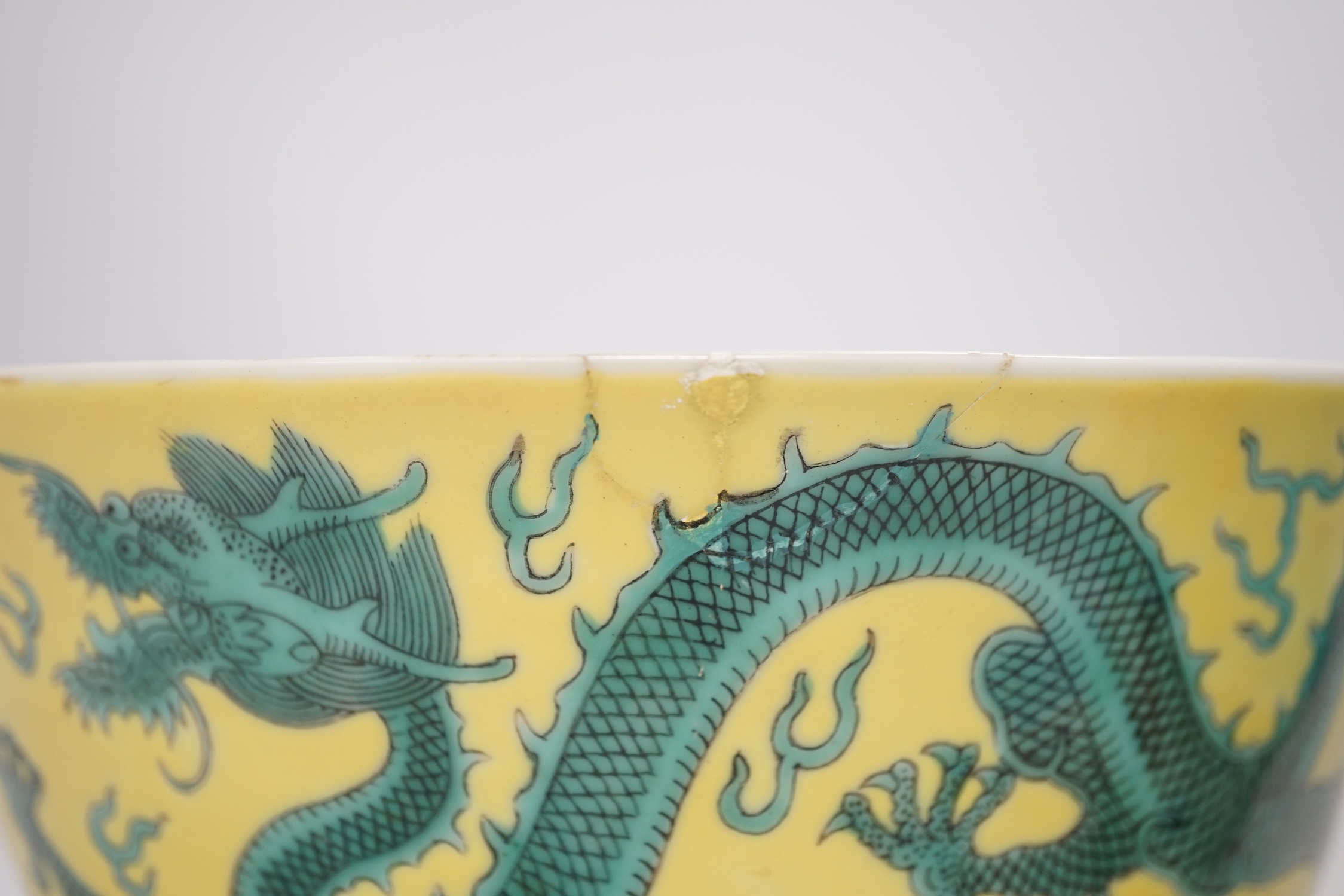 A Chinese yellow ground 'dragon' bowl, probably late Qing dynasty, and a similar floral cup, bowl 9cm high, 18.5cm diameter. Condition - bowl has a large section restored